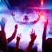 Male deejay in headphones and sunglasses looking at dancing crowd